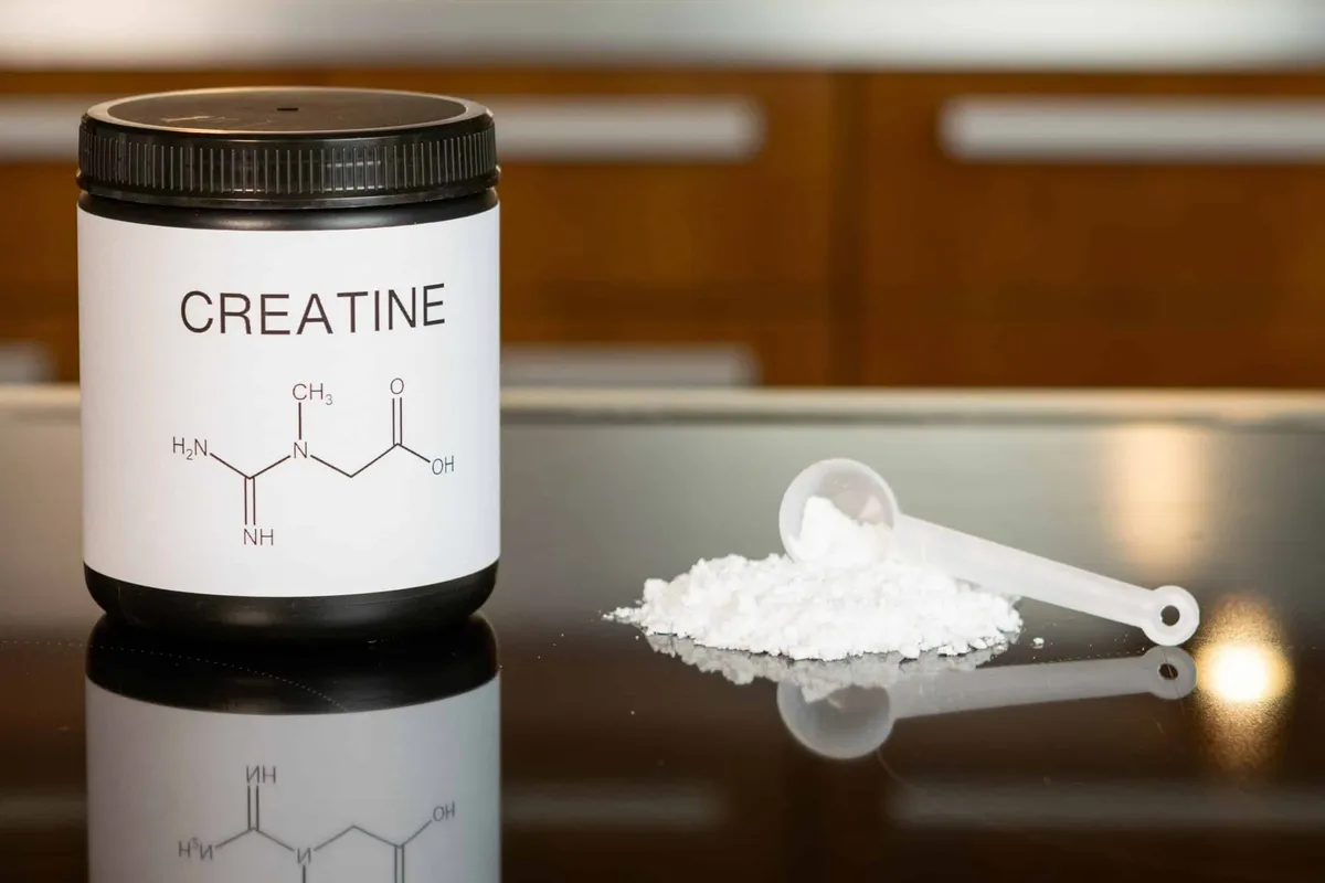 Closeup of scoop with creatine monohydrate supplement and chemical formula