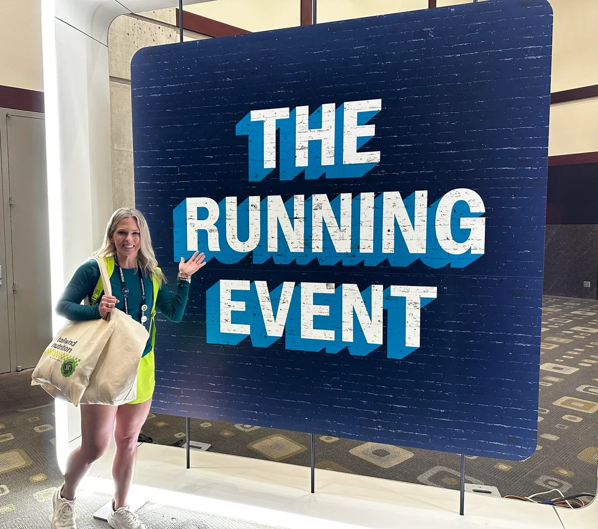 Jena Brown RD standing in front of The Running Event 2024 sign